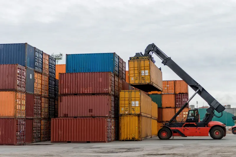 Reach stacker movimentando contêiner no pátio de um terminal portuário